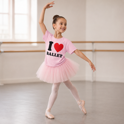 Young dancer in a ballet studio wearing a pink 'I love ballet' shirt and tutu.